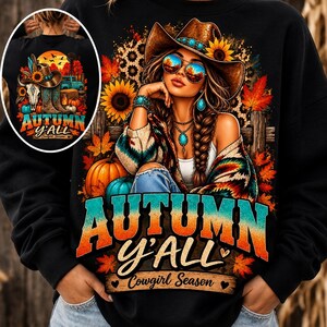 Peut inclure: Un sweat-shirt noir avec une illustration d'une personne portant un chapeau de cow-boy et des lunettes de soleil, entourée de tournesols, de citrouilles et de feuilles d'automne. Le texte indique "AUTUMN Y'ALL" et "Cowgirl Season".