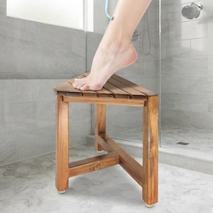 May include: A triangular shower stool crafted from brown wood with a slatted top surface and four sturdy legs. The stool features a cross-brace support structure between the legs and includes small white protective feet at the base of each leg.