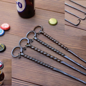 Op de afbeelding: Vier gedraaide metalen flessenopeners met een lusvormige handgreep. De openers liggen op een houten oppervlak.