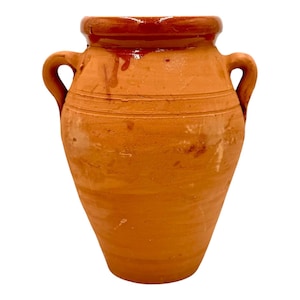 May include: A terracotta clay vessel featuring a wide, rounded body and two side handles. The upper rim and neck area are finished with a smooth, dark brown glazed coating, while the main body displays a natural, matte orange-brown texture.