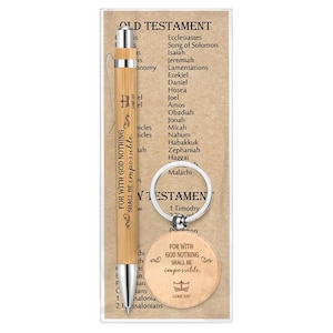 May include: A light brown bamboo pen and a matching circular wooden keychain, both engraved with the text "FOR WITH GOD NOTHING SHALL BE impossible." and a cross symbol. They are displayed on a card listing Old Testament book titles.