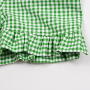 May include: Green and white gingham fabric with a ruffled edge.