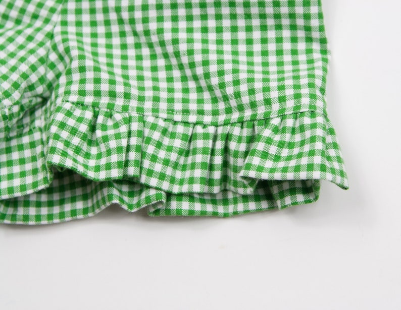 May include: Green and white gingham fabric with a ruffled edge.