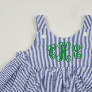 K&ouml;nnte beinhalten: Ein blaues und wei&szlig; gestreiftes, &auml;rmelloses Kleid mit einem gr&uuml;nen gestickten Monogramm "E.F.G."