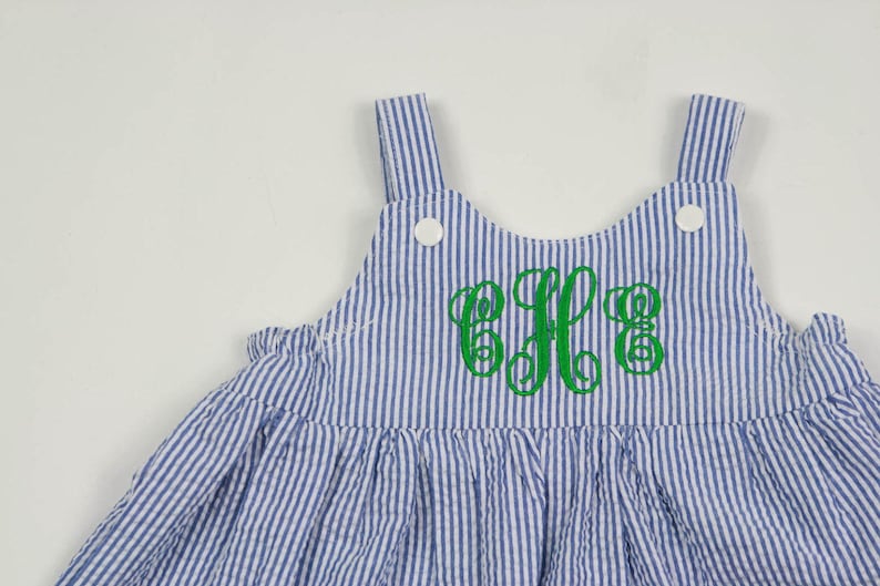 K&ouml;nnte beinhalten: Ein blaues und wei&szlig; gestreiftes, &auml;rmelloses Kleid mit einem gr&uuml;nen gestickten Monogramm "E.F.G."