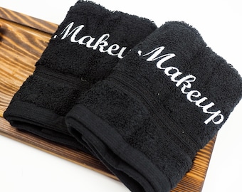 May include: Two black towels with white embroidery. The top towel says "Make" and the bottom towel says "Makeup".