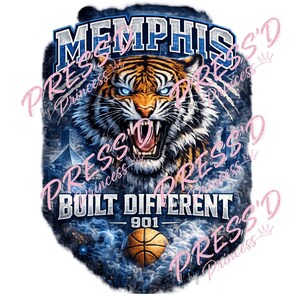 Puede incluir: Un diseño gráfico que muestra una cabeza de tigre gruñendo con ojos azules, debajo de la palabra MEMPHIS en letras azules negritas. Debajo del tigre, el texto dice BUILT DIFFERENT 901 sobre un balón de baloncesto, con un fondo azul ahumado.