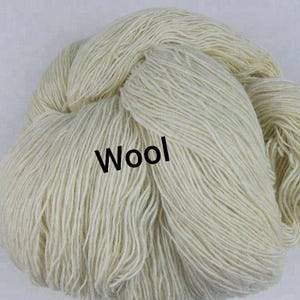 May include: A large, circular skein of off-white, natural-colored yarn with a soft, fibrous texture. The word Wool is printed in bold, black, sans-serif capital letters across the center of the yarn bundle, clearly visible against the light fibers.