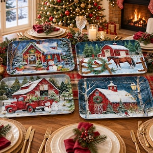 May include: Four rectangular serving trays featuring winter scenes with red barns, snow-covered landscapes, a snowman, a horse, and a red pickup truck loaded with gifts, arranged on a dining table set with plates and holiday decor.