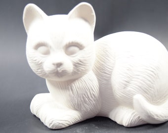 May include: White ceramic cat figurine with a detailed fur texture. The cat is lying down with its head turned to the side and its eyes closed.