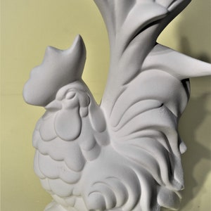 May include: White ceramic rooster figurine with a detailed design. The rooster is standing with its tail feathers spread out behind it.
