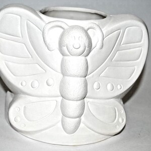 May include: White ceramic planter shaped like a butterfly with a raised design. The planter has a round opening at the top for planting.