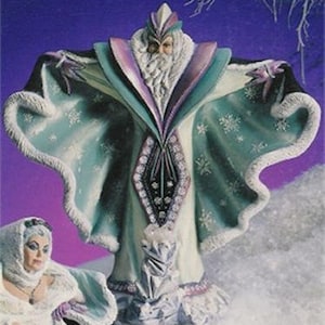 May include: A ceramic figurine of a winter wizard wearing a long, flowing robe with a green and white snowflake pattern. The wizard has a long white beard and a crown on his head.