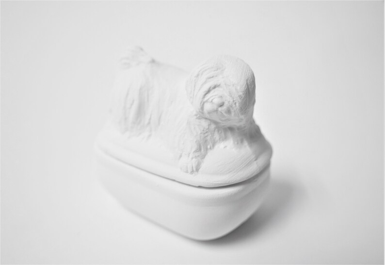 K&ouml;nnte beinhalten: Wei&szlig;e Keramik-Schmuckdose in Form eines Hundes, mit einem Deckel, der eine detaillierte Skulptur eines liegenden Hundes zeigt.