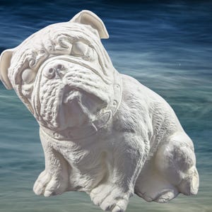 May include: A white bulldog statue with detailed facial features and a collar. The sculpture is sitting, with its front paws extended. The background is a blurred image of water.