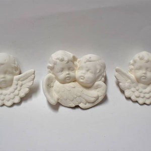 May include: Three white ceramic angel figurines with wings. The angels have cherubic faces and are in various poses.