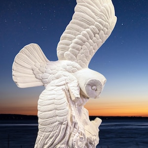 May include: A white owl sculpture with outstretched wings, perched on a tree trunk. The owl's feathers are intricately detailed, and the sculpture is set against a backdrop of a starry night sky and a body of water.