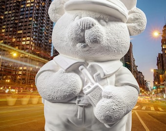 May include: White ceramic figurine of a teddy bear dressed as a police officer. The bear is wearing a hat, a shirt, and pants. The bear is holding a walkie-talkie in its right hand.