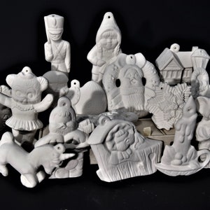 May include: A collection of unpainted ceramic figurines, including a toy soldier, gnome, bear, houses, and other holiday-themed ornaments. These bisque pieces are ready for painting and customization.