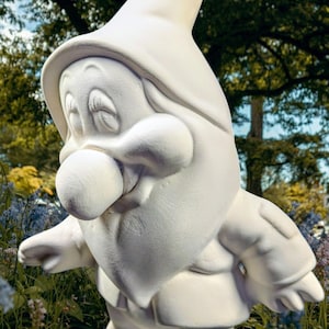 May include: A white ceramic garden gnome statue with a large nose, hat, and beard. The gnome is standing in a garden setting with flowers and trees in the background. The statue is unpainted and ready for customization.
