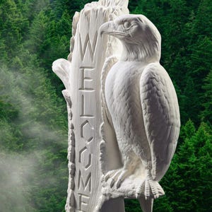 May include: A white, carved eagle statue perched on a tree trunk with the word "WELCOME" carved into the wood. The eagle has detailed feathers and a sharp beak. The background is a blurred forest of green trees.