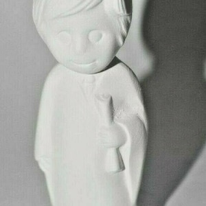 May include: White ceramic figurine of a graduate wearing a cap and gown. The figurine is holding a scroll in one hand.