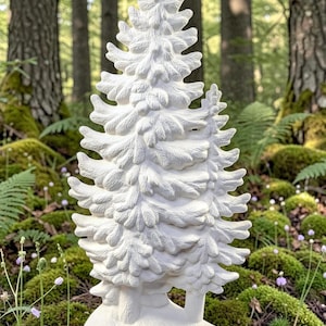 May include: A white, detailed ceramic fir tree sculpture. The tree has a textured surface with visible branches and needles. It stands on a base, set against a backdrop of a forest floor with moss and trees.