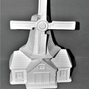 May include: White ceramic windmill figurine with a small house at the base. The windmill has a cross-shaped blade and a round opening at the top. The house has a gabled roof and two windows on each side.