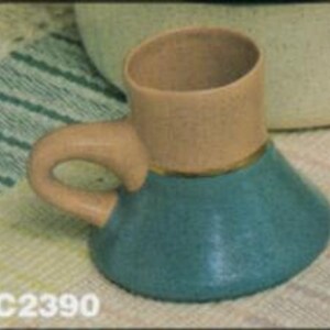 May include: A small, teal-colored ceramic mug with a light brown handle and a gold trim. The mug has a wide, flared base and a narrow top.