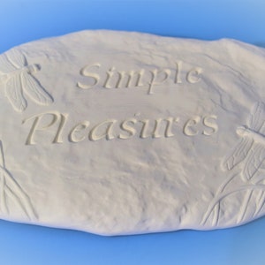 May include: White ceramic garden stone with the words "Simple Pleasures" engraved on it. The stone is decorated with dragonfly designs.
