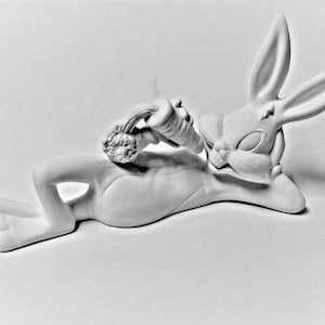 May include: A white ceramic figurine of Bugs Bunny lying down with a carrot in his hand.