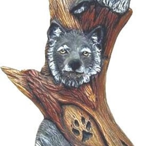 May include: A wooden sculpture of three grey wolves, two are howling and one is peeking out from behind a tree trunk. The sculpture is painted in shades of brown and grey.