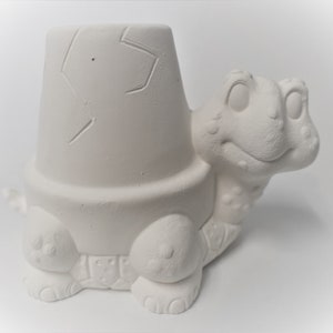 May include: White ceramic turtle planter with a pot on its back. The planter is ready to be painted.