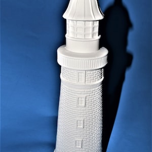 May include: White ceramic lighthouse figurine with a detailed brick pattern and a domed roof. The lighthouse has a small door and several windows.