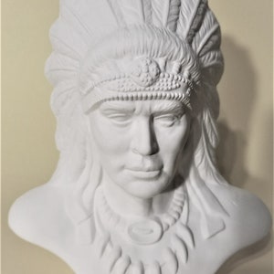 May include: White ceramic bust of a Native American man wearing a headdress with feathers. The bust is unpainted and ready to be decorated.