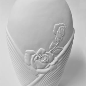 May include: White ceramic vase with a raised design of roses. The vase has a smooth, matte finish and a round, slightly oval shape.