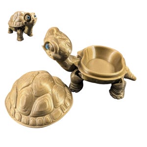 May include: A gold-colored turtle-shaped trinket box with a hinged lid. The turtle has a detailed shell and large, expressive eyes.