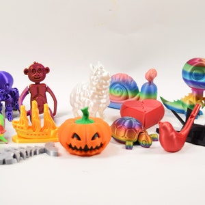 May include: A collection of 3D printed figurines in various colors and designs, including a pumpkin, a snail, a dinosaur, a llama, a monkey, an octopus, a ship, a skeleton, a bird, a helicopter, a turtle, a mouse, a rabbit, a crocodile, and a person.