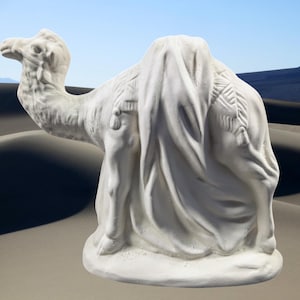 May include: A white, detailed sculpture of a camel, draped with a textured cloth. The camel is posed in a seated position, with its head turned to the left. The sculpture has a matte finish and is set against a desert backdrop.