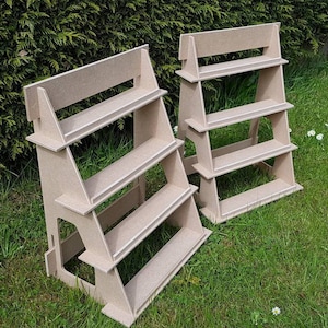May include: Two wooden display stands with three shelves each. The stands are made of light brown wood and have a simple, rustic design.
