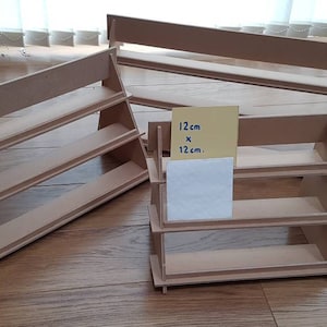 May include: Three wooden display shelves, each with three tiers. The shelves are made of natural brown wood and are 12 inches by 12 inches. The shelves are perfect for displaying small items, such as jewelry, figurines, or candles.