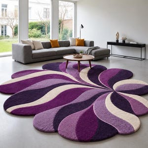 May include: A large, flower-shaped area rug featuring a tufted, high-pile texture. The design consists of radiating, curved segments in alternating shades of deep purple, light violet, and cream, creating a swirling, petal-like pattern.