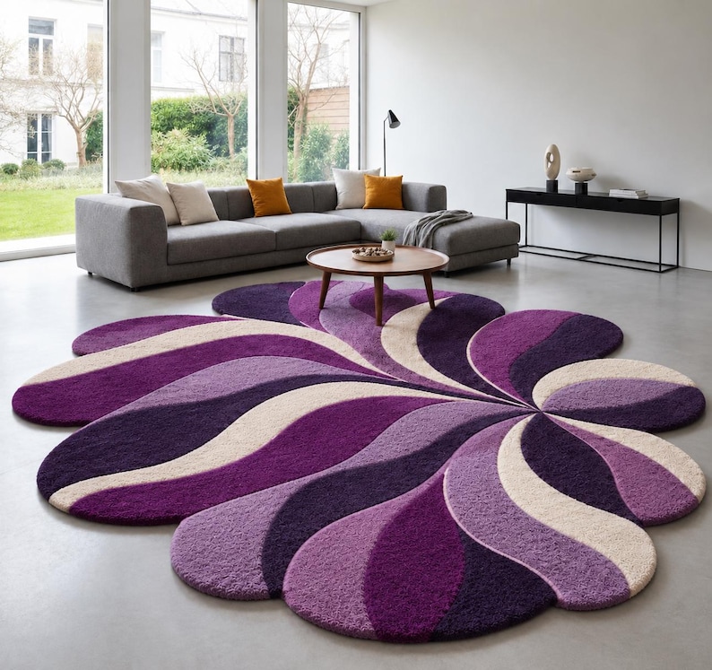 May include: A large, flower-shaped area rug featuring a tufted, high-pile texture. The design consists of radiating, curved segments in alternating shades of deep purple, light violet, and cream, creating a swirling, petal-like pattern.