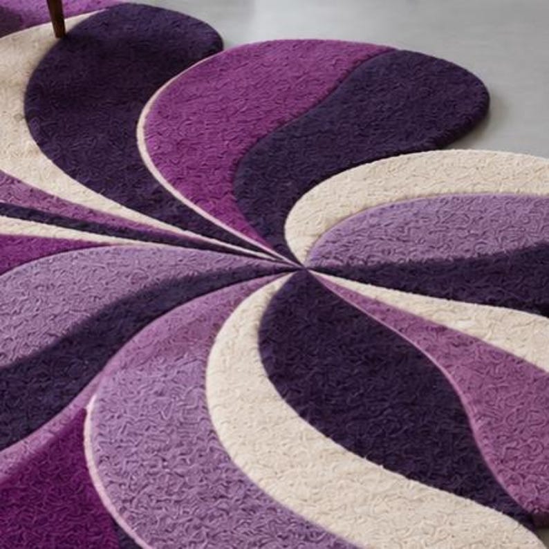 May include: A circular area rug featuring a swirling, pinwheel-inspired pattern. The design consists of alternating curved segments in deep purple, light lavender, and cream, all rendered in a textured, tufted pile with a consistent surface finish.