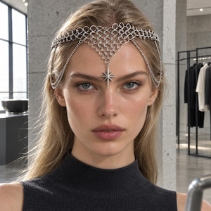 May include: A silver-toned headpiece featuring a delicate chainmail-style mesh that rests across the forehead. The accessory is adorned with a central eight-pointed star charm and includes additional thin silver chains draping along the sides.