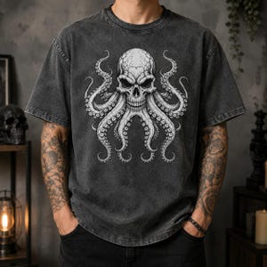 Könnte beinhalten: Ein anthrazitfarbenes, säuregewaschenes Kurzarm-T-Shirt mit einem großen, detaillierten weißen Grafikdruck eines menschlichen Schädels, der mit Krakenarmen kombiniert ist. Das Design ist mittig auf der Brust platziert und zeigt feine Schattierungen.