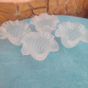Peut inclure: Un ensemble de quatre abat-jours en verre dépoli, chacun présentant un bord délicatement volanté et un motif nervuré en spirale subtil. Ces couvercles en verre translucide en forme de bol ont une finition mate douce et une large ouverture.