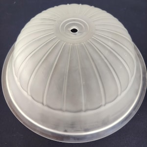 Op de afbeelding: Een koepelvormige lampenkap van matglas met een geribbeld, gecanneleerd patroon dat uitstraalt vanuit een centrale ronde opening aan de bovenkant. De kap is voorzien van een gladde, heldere glazen rand aan de onderzijde.