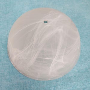 Puede incluir: Una pantalla de lámpara de vidrio en forma de cúpula con un acabado blanco translúcido y patrones de remolinos similares a nubes en toda la superficie. La pantalla tiene una única abertura circular en el centro superior para su montaje.