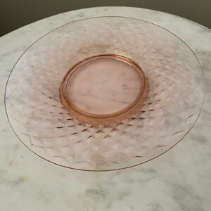 May include: A pink glass bowl with a diamond pattern. The bowl is clear and has a textured surface.